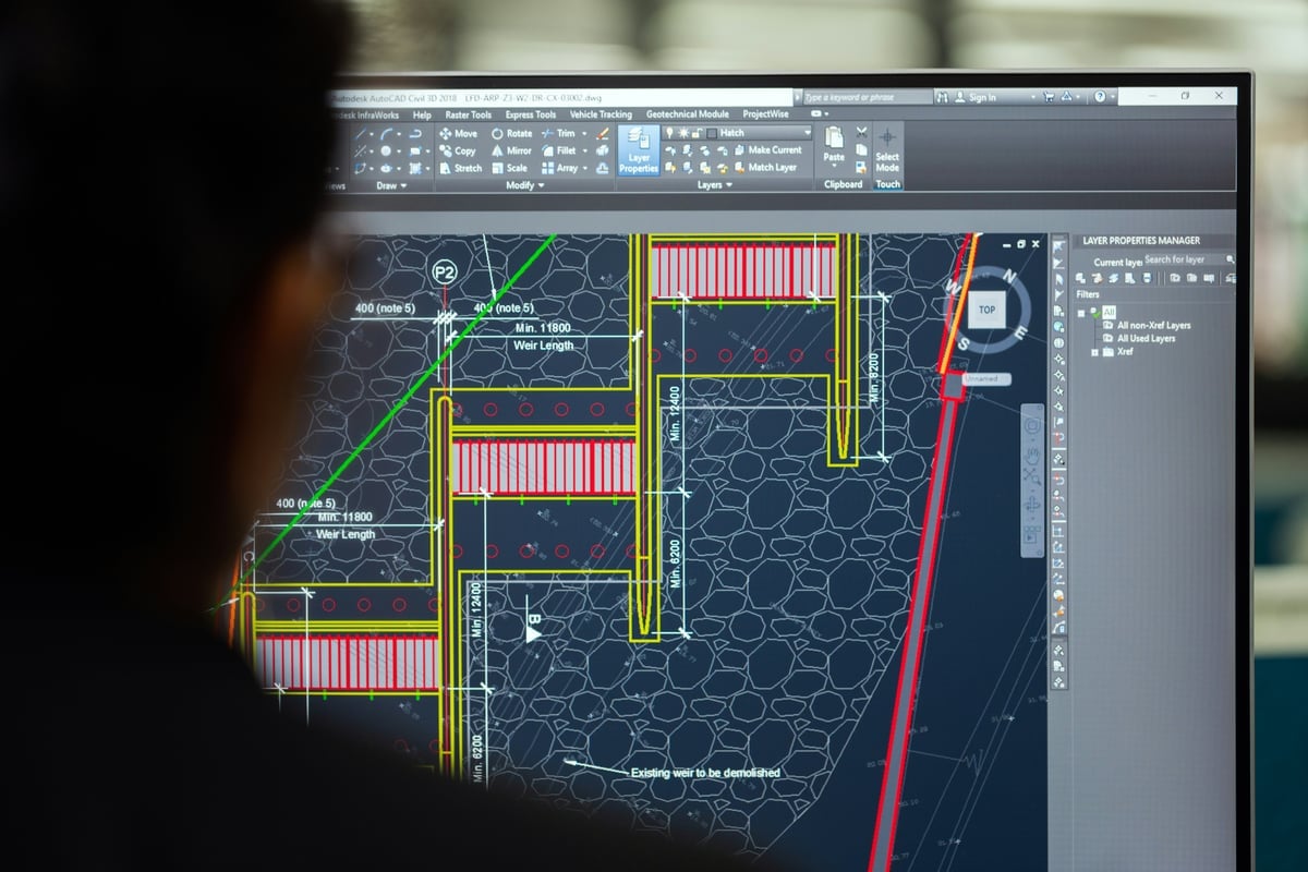 A structural civil engineer reviewing a detailed CAD drawing with dimensions and structural details.